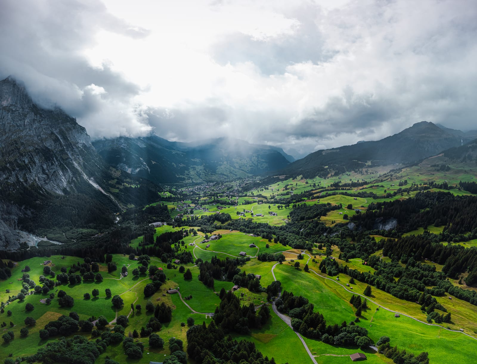 Aerial: green valley under dramatic storm light.